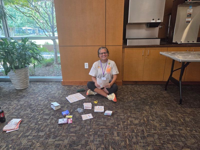 Volunteer standing with accessibility support-card materials at Bash