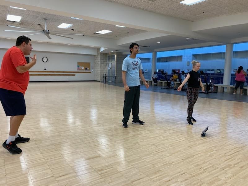 Adult adaptive-dance participant moving with an instructor in class